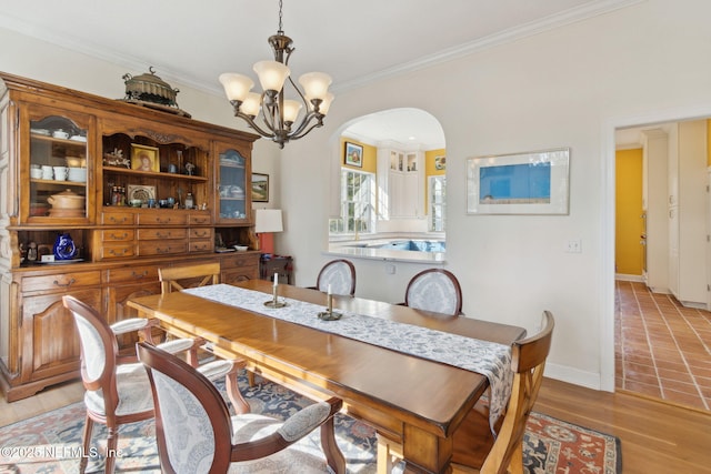 dining space featuring ornamental molding, a chandelier, and light wood-type flooring