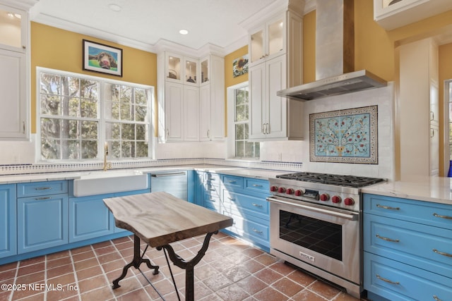 kitchen featuring white cabinets, appliances with stainless steel finishes, blue cabinets, and wall chimney range hood