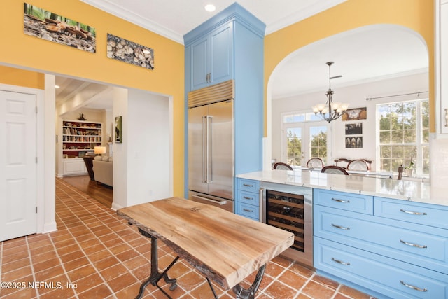 kitchen featuring wine cooler, blue cabinetry, decorative light fixtures, ornamental molding, and stainless steel built in fridge