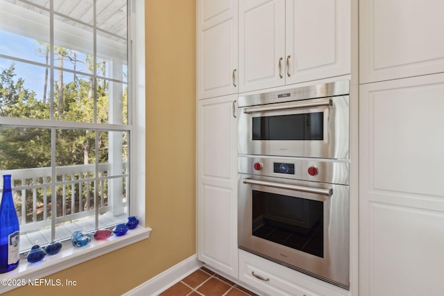 kitchen with white cabinetry, double oven, and dark tile patterned floors