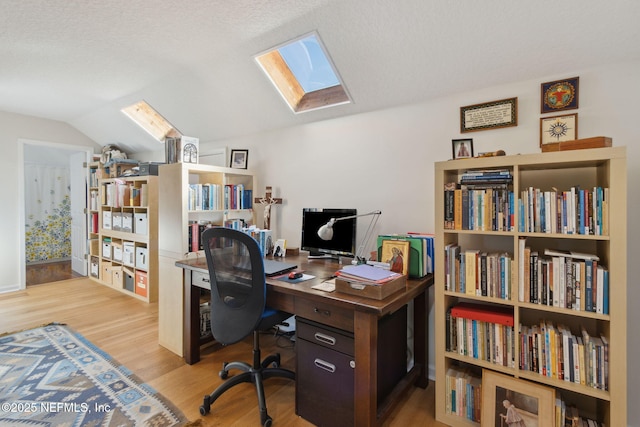 home office featuring vaulted ceiling with skylight, a textured ceiling, and light wood-type flooring