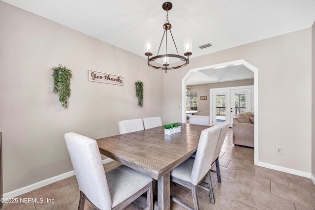 dining space with french doors and a chandelier