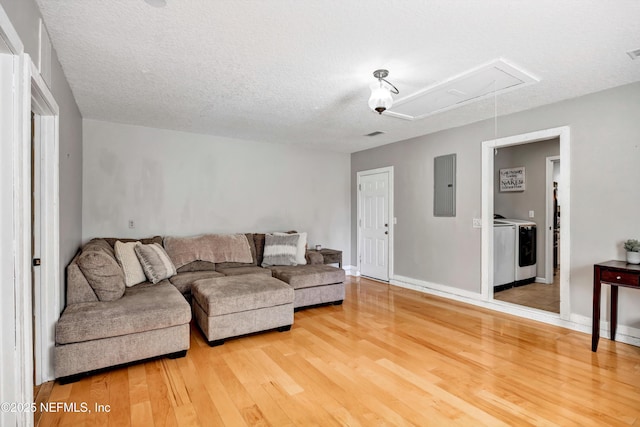 living room featuring hardwood / wood-style floors, a textured ceiling, electric panel, and washing machine and clothes dryer