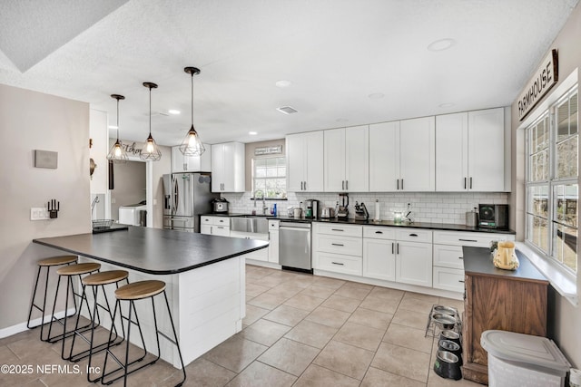 kitchen featuring hanging light fixtures, stainless steel appliances, tasteful backsplash, white cabinets, and kitchen peninsula