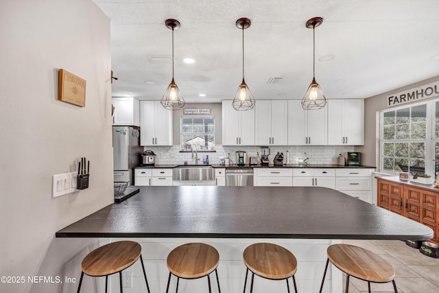 kitchen with stainless steel appliances, white cabinets, a kitchen breakfast bar, and decorative light fixtures