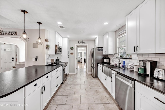 kitchen with sink, white cabinetry, decorative light fixtures, light tile patterned floors, and appliances with stainless steel finishes