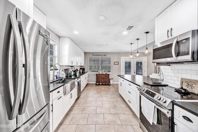 kitchen with pendant lighting, sink, white cabinets, stainless steel appliances, and french doors