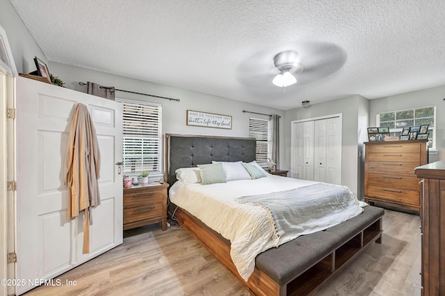 bedroom with a closet, ceiling fan, a textured ceiling, and light hardwood / wood-style flooring