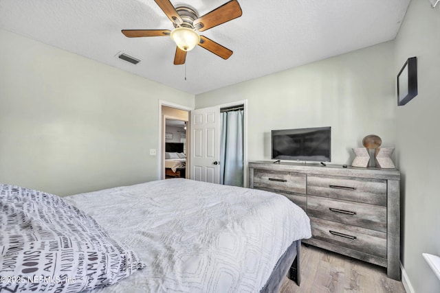 bedroom featuring ceiling fan, a textured ceiling, and light wood-type flooring