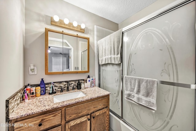 bathroom with vanity, combined bath / shower with glass door, and a textured ceiling