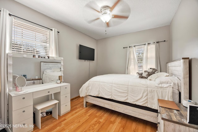 bedroom with ceiling fan, a textured ceiling, and light wood-type flooring