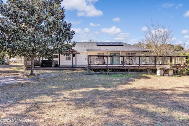 rear view of house with a lawn, solar panels, and a deck