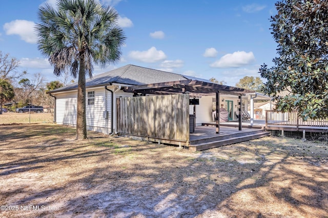 rear view of house with a wooden deck and a pergola