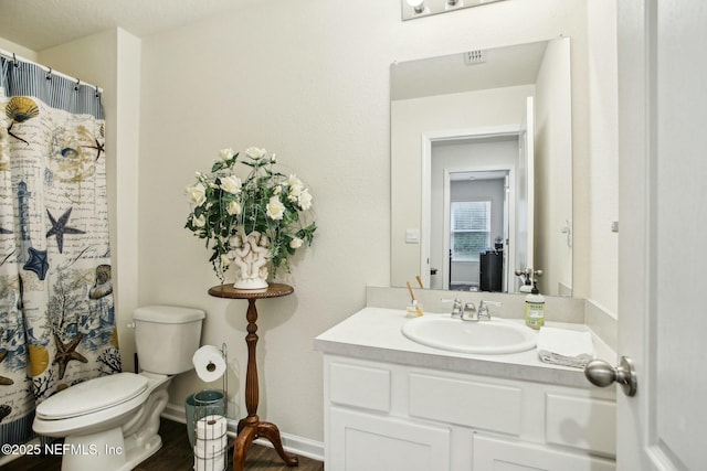 bathroom featuring vanity, curtained shower, and toilet