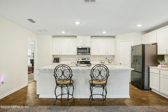 kitchen featuring white cabinetry, appliances with stainless steel finishes, a center island with sink, and dark hardwood / wood-style flooring