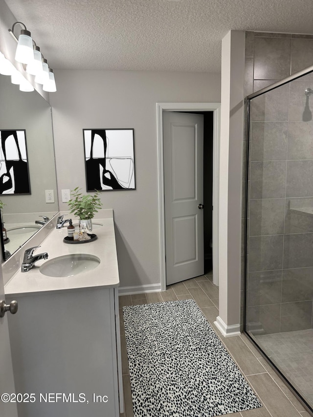 bathroom featuring vanity, a shower with shower door, and a textured ceiling