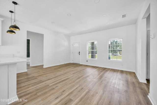 unfurnished living room featuring visible vents, baseboards, and light wood-style floors