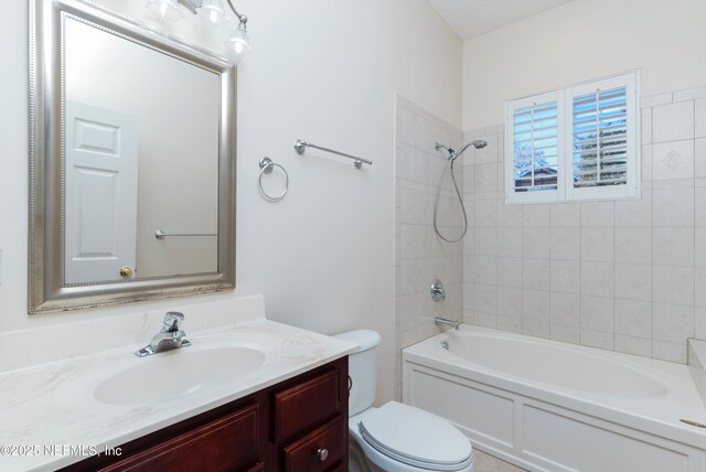 full bathroom featuring vanity, tiled shower / bath, and toilet