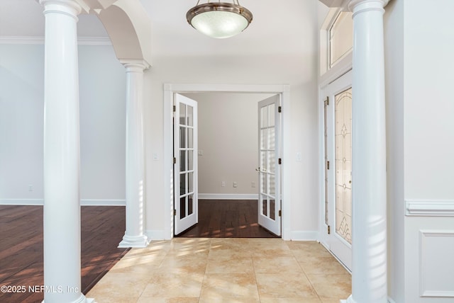 tiled foyer entrance featuring crown molding, decorative columns, and french doors