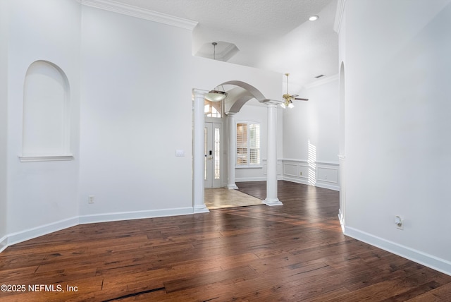 unfurnished room featuring ornate columns, a textured ceiling, ornamental molding, dark hardwood / wood-style floors, and ceiling fan