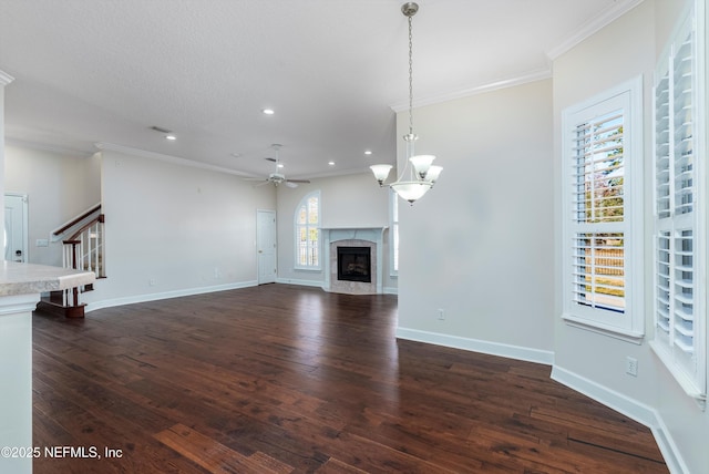 unfurnished living room with dark hardwood / wood-style flooring, crown molding, and ceiling fan with notable chandelier