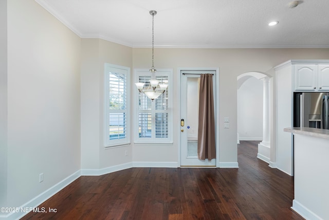 unfurnished dining area with crown molding, dark hardwood / wood-style floors, and ornate columns