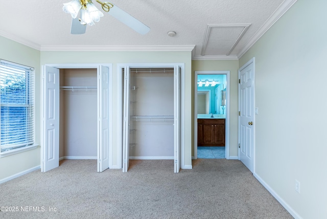 unfurnished bedroom with multiple closets, crown molding, light carpet, and a textured ceiling