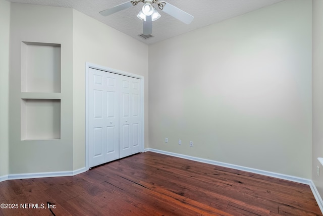 unfurnished bedroom featuring ceiling fan, dark wood-type flooring, a closet, and a textured ceiling