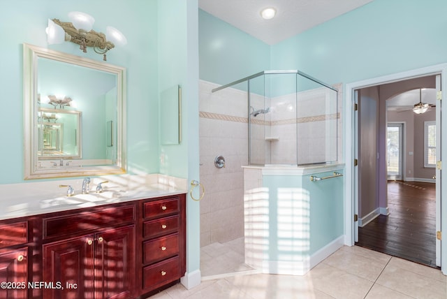 bathroom featuring walk in shower, ceiling fan, tile patterned floors, and vanity