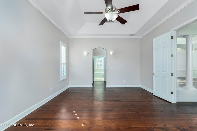 unfurnished room with ornate columns, ornamental molding, dark hardwood / wood-style floors, a raised ceiling, and ceiling fan