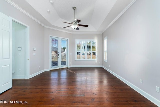 empty room with a textured ceiling, ornamental molding, dark hardwood / wood-style floors, a raised ceiling, and ceiling fan