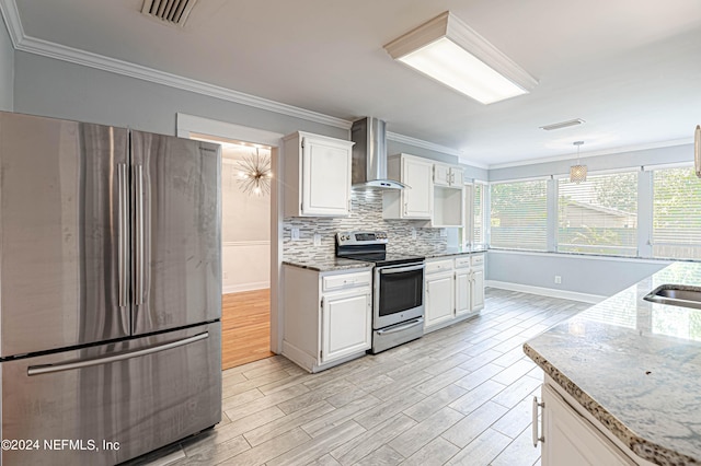 kitchen featuring white cabinets, stainless steel appliances, hanging light fixtures, and wall chimney exhaust hood