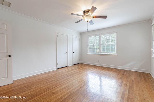 unfurnished bedroom featuring crown molding, ceiling fan, multiple closets, and light wood-type flooring