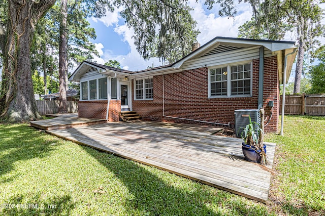 rear view of house featuring central AC unit, a yard, and a wooden deck