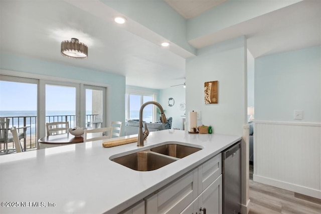 kitchen with sink, dishwasher, white cabinetry, a water view, and light hardwood / wood-style floors