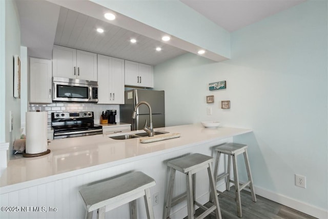 kitchen with white cabinetry, a breakfast bar area, stainless steel appliances, and kitchen peninsula