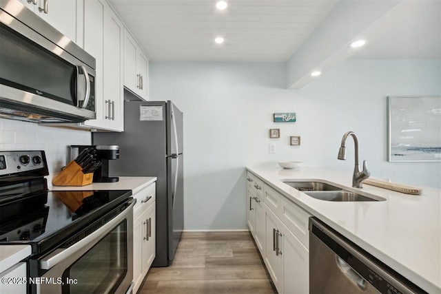 kitchen with sink, backsplash, stainless steel appliances, and white cabinets