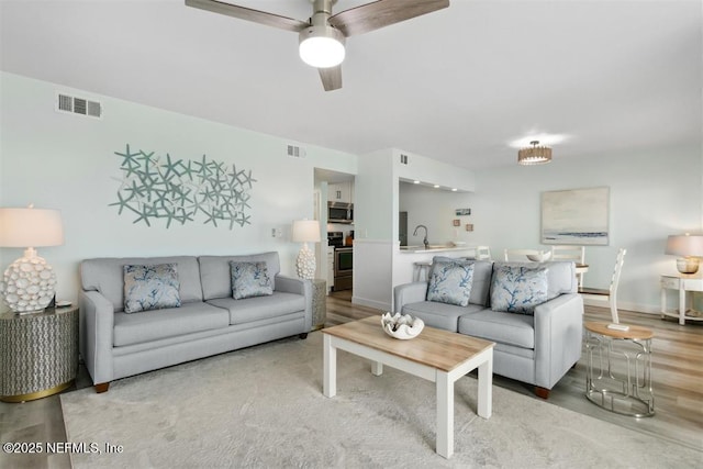 living room featuring ceiling fan, sink, and hardwood / wood-style floors