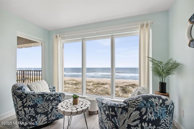 interior space with a view of the beach, a wealth of natural light, and a water view