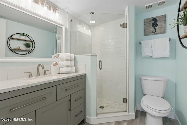 bathroom with an enclosed shower, vanity, hardwood / wood-style flooring, and toilet