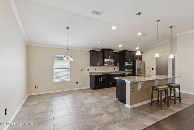 kitchen featuring crown molding, a kitchen breakfast bar, stainless steel appliances, an island with sink, and decorative light fixtures