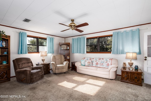 living room with ceiling fan, ornamental molding, and carpet