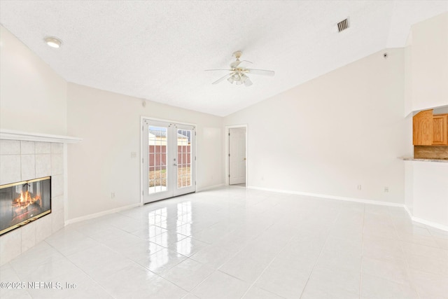 unfurnished living room featuring a tile fireplace, lofted ceiling, light tile patterned flooring, and french doors