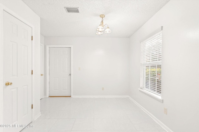 empty room featuring a notable chandelier and a textured ceiling