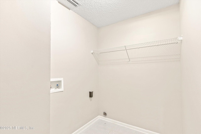 washroom with washer hookup, hookup for an electric dryer, a textured ceiling, and light tile patterned floors