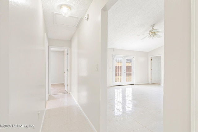 hallway featuring light tile patterned flooring, lofted ceiling, and french doors