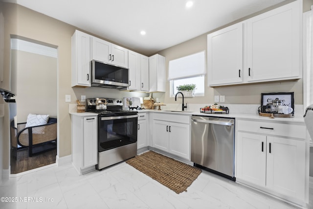 kitchen with appliances with stainless steel finishes, sink, and white cabinets