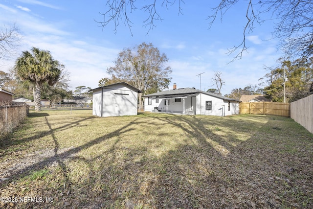 rear view of property with a yard and a storage unit