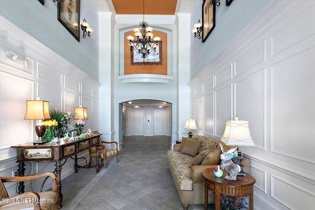 entryway with crown molding, a chandelier, and a towering ceiling