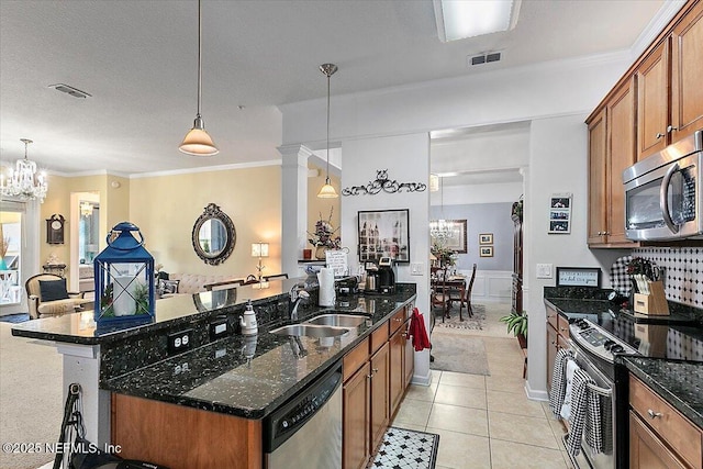 kitchen with sink, decorative light fixtures, stainless steel appliances, and dark stone counters